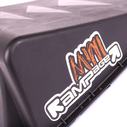 Close-up of a black Rampage Single Mini Launch Skate Ramp featuring a white and orange "Rampage" logo on the side. Ideal for skating and scootering enthusiasts, its surface includes subtle triangular patterns for enhanced grip.