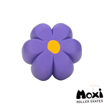 The Moxi Brake Petal Roller Skate Toe Stops - Violet are designed as a vibrant purple flower-shaped brake cover, complete with a yellow center, making them an ideal accessory for roller skates. These durable toe stops, featuring the Moxi logo in the bottom right corner, offer a perfect blend of style and functionality.