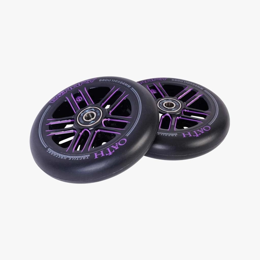 Positioned diagonally on a plain white background are two Oath Binary 110mm stunt scooter wheels in black with purple accents. These lightweight hollow-core wheels come equipped with high-grade Oath Fidelity bearings, and each wheel is adorned with the text "OATH.