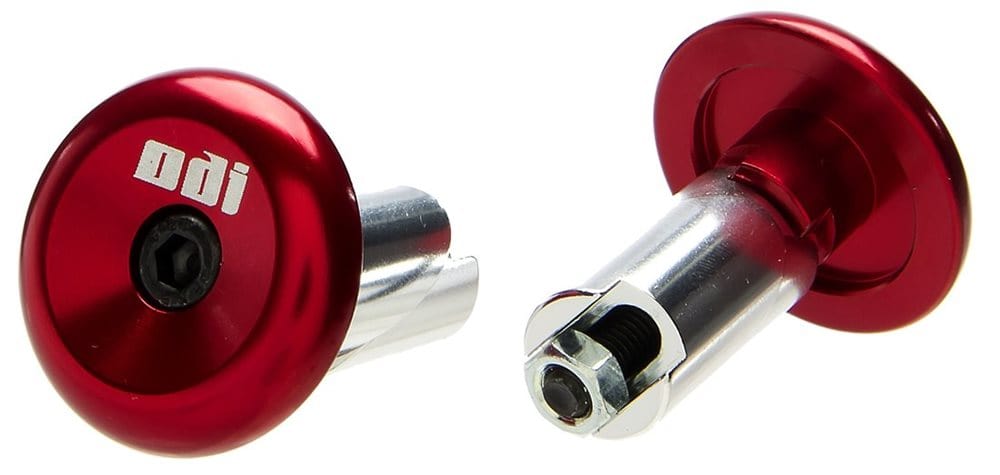 The ODI Aluminium Stunt Scooter Bar Ends in metallic red feature a bolt mechanism and an adjustable triple-core design, showcasing the "ODI" logo. Made from durable aluminum, these bar ends are perfect for bike or scooter handlebars and are displayed against a white background.