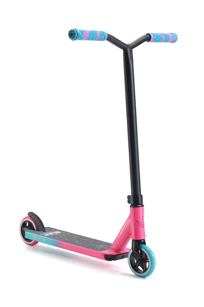 The Blunt Envy ONE S3 Complete Stunt Scooter in Pink and Teal is an ideal choice for beginner riders, boasting a vibrant mix of colors. The scooter features stylish blue and pink patterned handle grips, a solid pink deck complemented by a black grip surface, sleek black handlebars, and striking black wheels with vibrant blue rims.