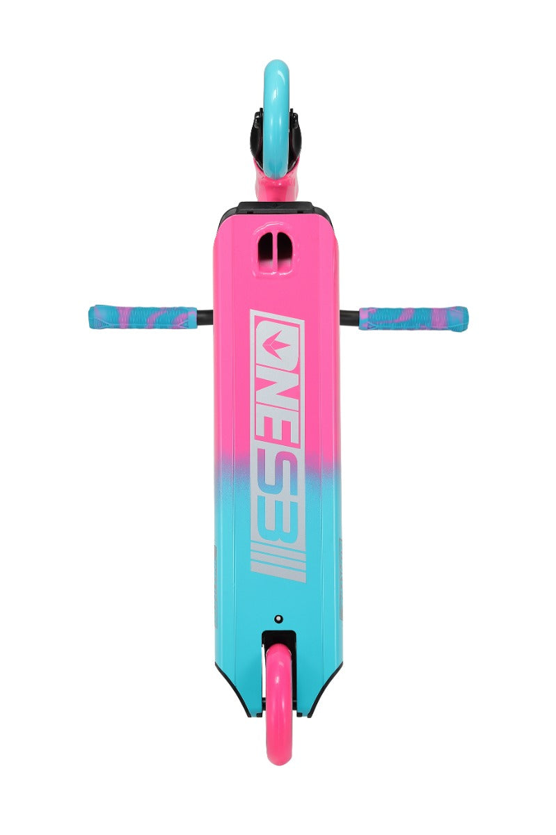 Top view of the Blunt Envy ONE S3 Complete Stunt Scooter deck in vibrant pink and teal, showcasing the stylized "ONES3I" logo. Ideal for beginner scooter riders, it features matching grips on the handle and a single visible wheel. The color transition is smooth, creating an eye-catching design reminiscent of the Blunt Envy One S3.