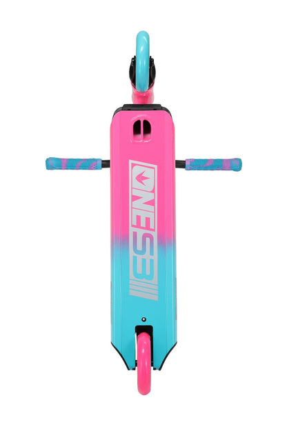 Top view of the Blunt Envy ONE S3 Complete Stunt Scooter deck in vibrant pink and teal, showcasing the stylized "ONES3I" logo. Ideal for beginner scooter riders, it features matching grips on the handle and a single visible wheel. The color transition is smooth, creating an eye-catching design reminiscent of the Blunt Envy One S3.