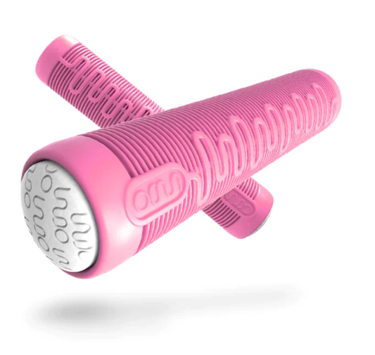 A pink silicone grip by INDO, featuring a textured finish with white accents, showcases a sleek cylindrical shape and an embossed wave design for enhanced control. It’s positioned diagonally with another similar grip partly visible in the background.