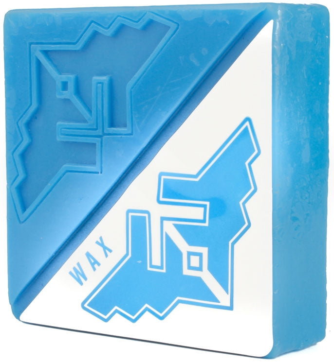 A block of Fracture Wings Skateboard Wax in blue showcases a geometric design with the word "WAX" on one side. Its angular cut emphasizes the contrast between the blue and white sections, reflecting Fracture's bold style.