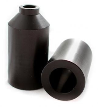 Two black cylindrical objects with hollow centers and tapered tops, resembling the Blunt Envy Aluminium Stunt Scooter Pegs, are displayed. One cylinder stands upright while the other rests horizontally beside it on a white background.