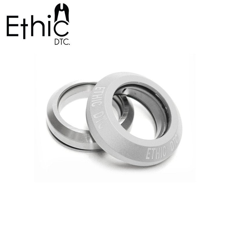 Two grey Ethic Basic integrated stunt scooter headset bearings are positioned side by side against a white background. They feature a sleek, round design with the Ethic brand name engraved on the surface, and their sealed bearings promise enhanced durability and performance.