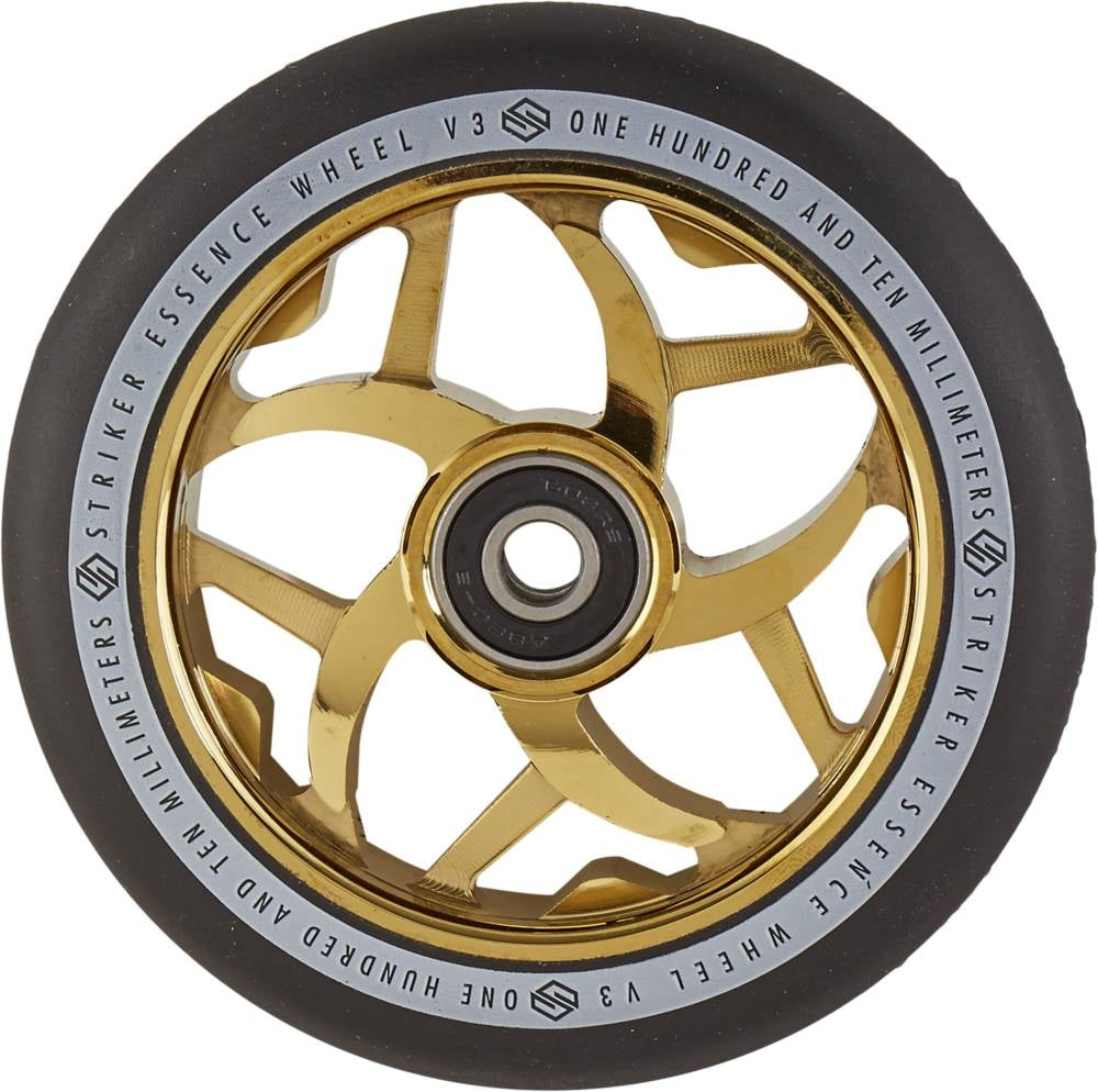 A detailed view of the Striker Essence V3 110mm Scooter Wheel showcases its metallic gold and black design, featuring a spoked aluminum core in a star-like pattern. The outer edge bears the words, "STRIKER ESSENCE WHEEL V3 ONE HUNDRED AND TEN MILLIMETERS," while the tire is equipped with an ABEC-9 bearing for an ultra-smooth finish.