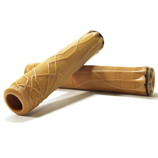 A pair of Ethic DTC Gum Stunt Scooter Grips in tan sit crossed against a white background. Made from thermoplastic rubber for extra durability, one grip stands upright while the other lies horizontally, highlighting the Ethic brand name and detailed design features.