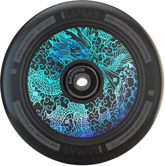 A close-up of the Lucky Lunar 110mm Stunt Scooter Wheel - Tattoo highlights its black rim, adorned with a vibrant dragon design in blue and teal on the hub. The rim features the text "Lunar," "One Hundred Ten Millimeters," and "Premium Brand Est. 2009," and incorporates Lucky Rebound Technology™ for smoother rides.