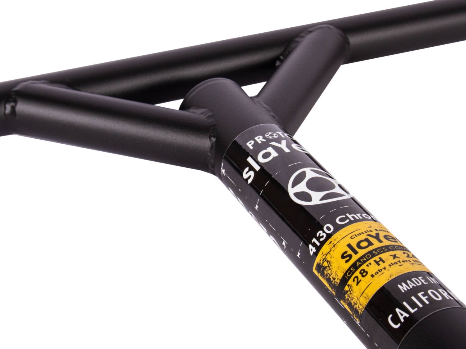 Close-up of the Proto Baby Slayer Classic Pro Steel SCS Stunt Scooter Bars in flat black metal, featuring branding. The decal reads "4130 Chromoly, 711mm Wide x 610mm Tall, Made in California," with logos highlighted by a yellow accent. This T-shaped chromoly steel design is reminiscent of the Classic Stunt Scooter Bar style.