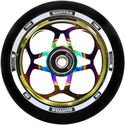 The Lucky Quatro Pro 110mm Scooter Wheel - Neochrome from Lucky showcases a black outer tire and a metallic multicolored hub with a star-shaped pattern. Enhanced by the Lucky Rebound Technology, the silver rim features "QUATRO" and "110MM" text, ensuring smooth rides and durability.