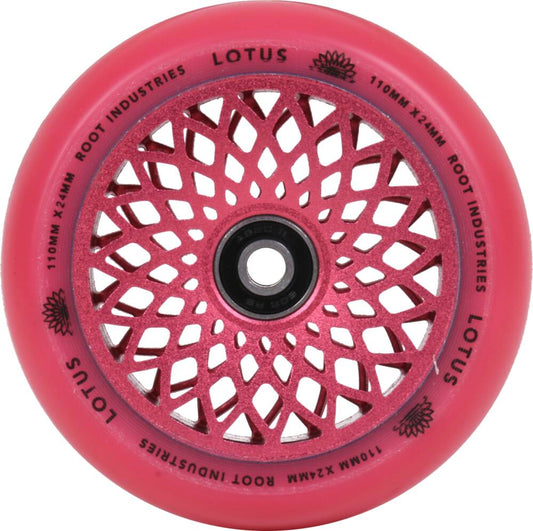 A radiant pink wheel with a black center and intricate, symmetric cutouts that form a lotus-like pattern is perfect for freestyle scootering. The Root Industries Lotus 110mm Scooter Wheel features the text "Lotus" and "Root Industries" printed around the edge.