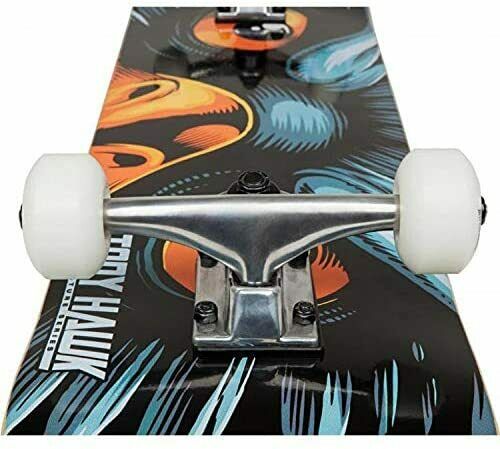 Close-up of the Tony Hawk 180 Series Eye Of The Hawk Complete Skateboard, featuring polished metal trucks and white wheels. The board displays a vibrant abstract design in orange, blue, and black, with the iconic "Tony Hawk" signature partially visible—an ideal choice for entry-level skaters seeking style and quality.