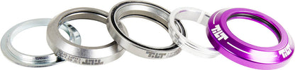 A set of five sleek, metallic, and plastic headset spacers is displayed in a row. These stylish silver and purple spacers include one featuring "Tilt" inscribed in white text. Each piece boasts a smooth, shiny finish, making them the perfect addition to your Tilt Integrated Stunt Scooter Headset - Purple setup.