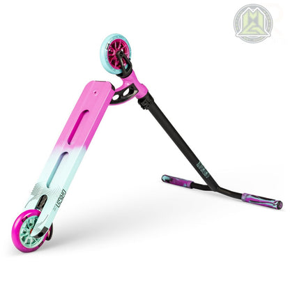 A Madd Gear MGP VX Origin Pro Complete Stunt Scooter is displayed on its side, revealing a sturdy and vibrant design. The deck elegantly shifts from pink to teal blue, accompanied by striking pink wheels. Black handlebars come with purple grips, and the logo is prominently visible in the top right corner of this lightweight scooter.